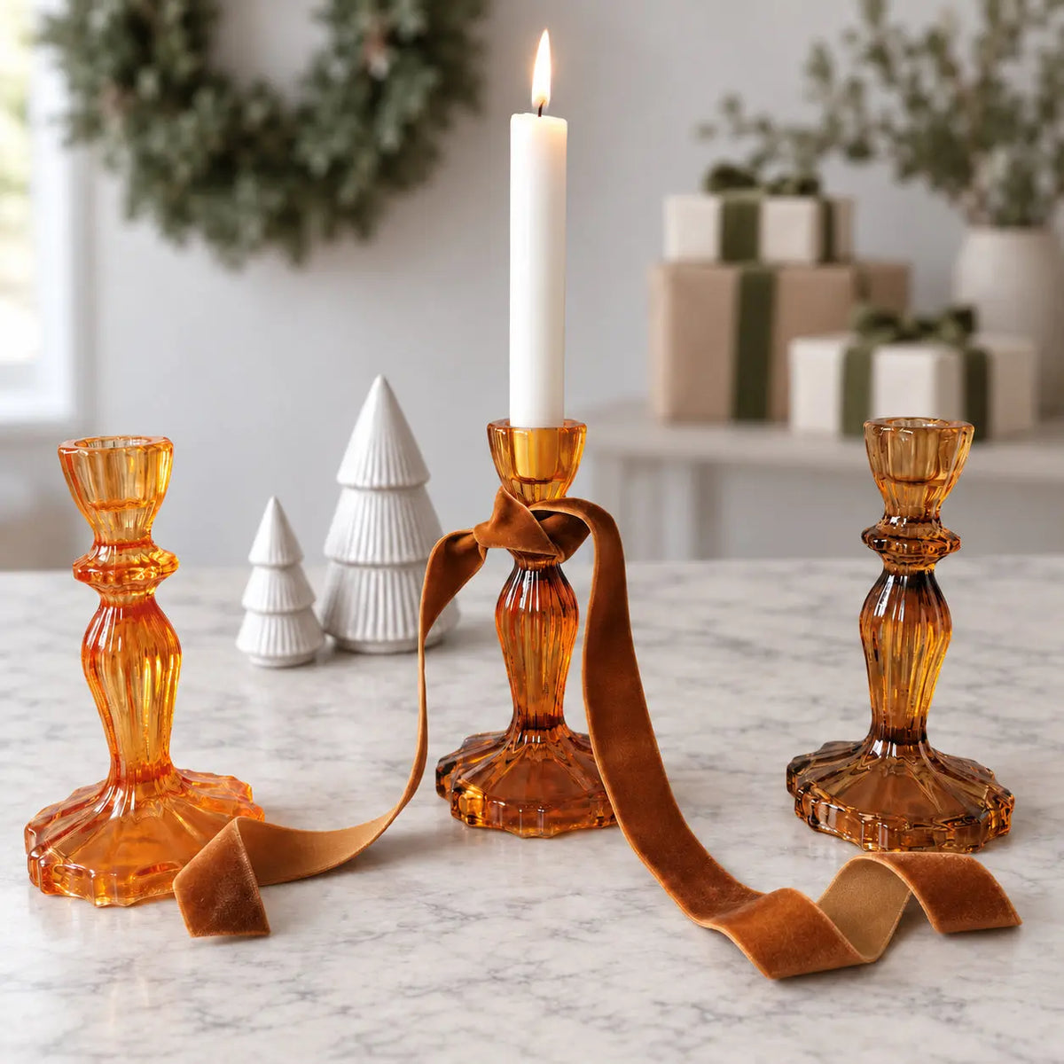 Festive candlestick holders styled with a white dinner candle, ribbon and ceramic Christmas trees.