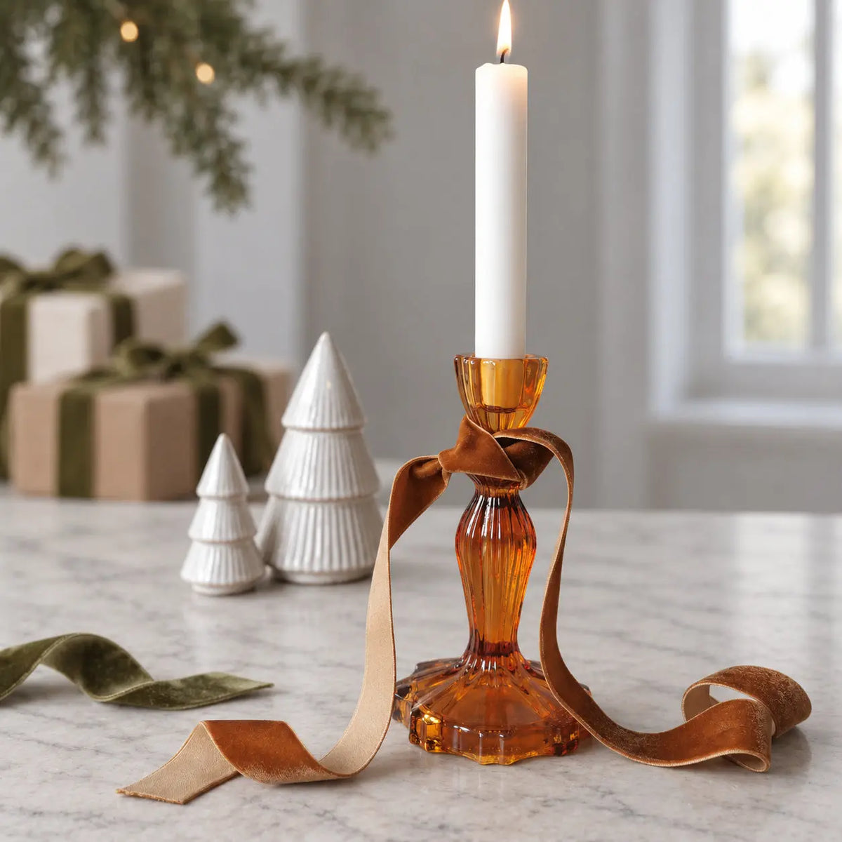 Amber candlestick holder held by its scalloped base, with two holders behind.