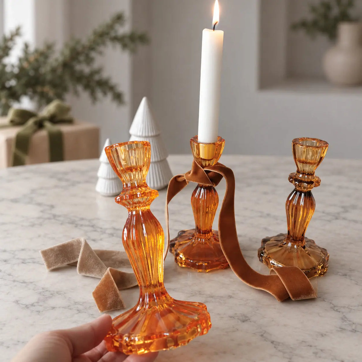 Orange-toned candlestick holder with a matching ribbon and a white dinner candle.