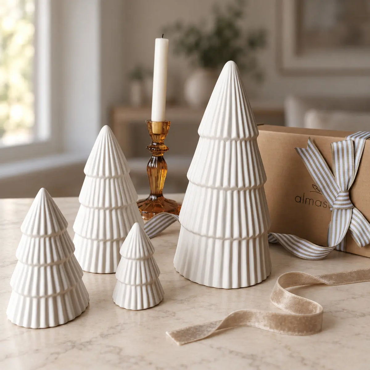  Four ribbed ceramic Christmas trees beside a gift box and amber candleholder by Almasea