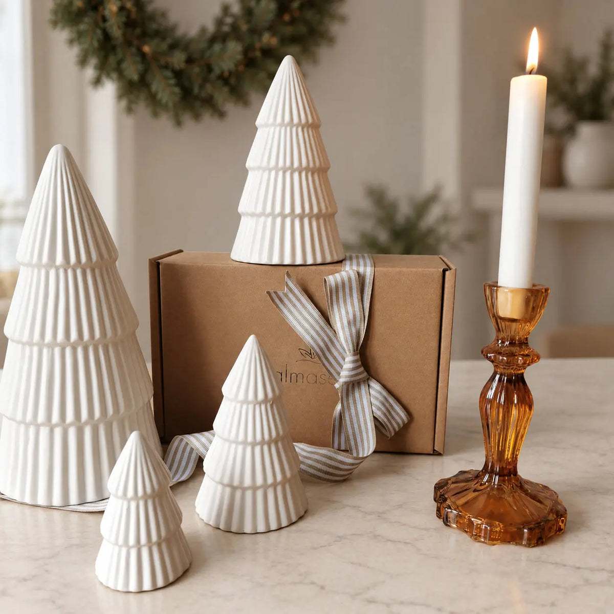 Four ribbed ceramic Christmas trees beside a gift box and amber candleholder by Almasea