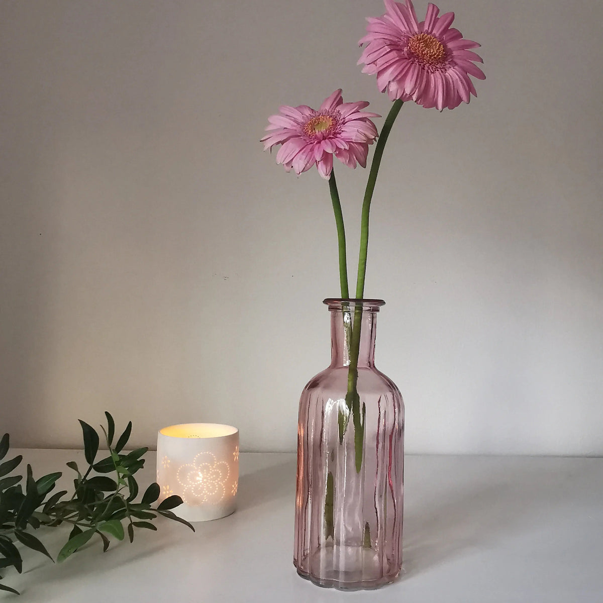 Ribbed pink glass vase holding a daisy